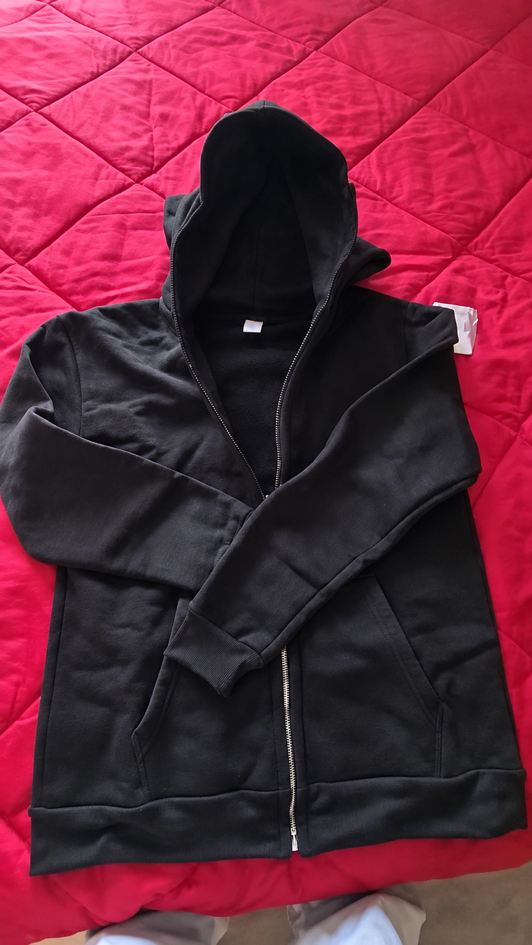 Black balaclava zip hoodie with crossed sleeves on a red quilt