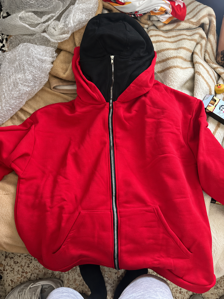 Red balaclava zip hoodie laid flat on a blanket